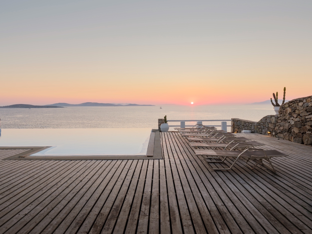Infinity pool deck at sunset with sunbeds